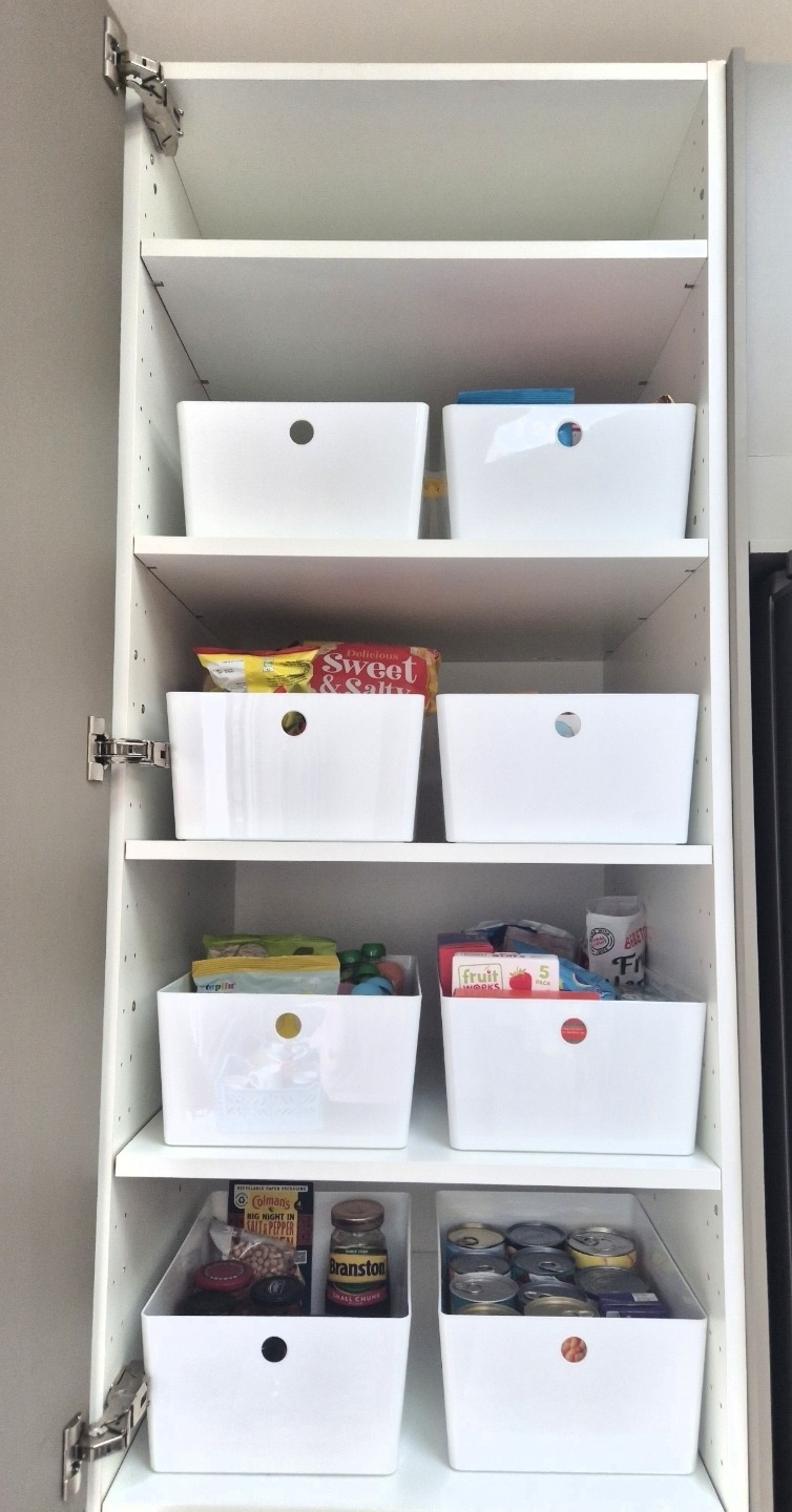 Organised kitchen cupboard with white storage boxes